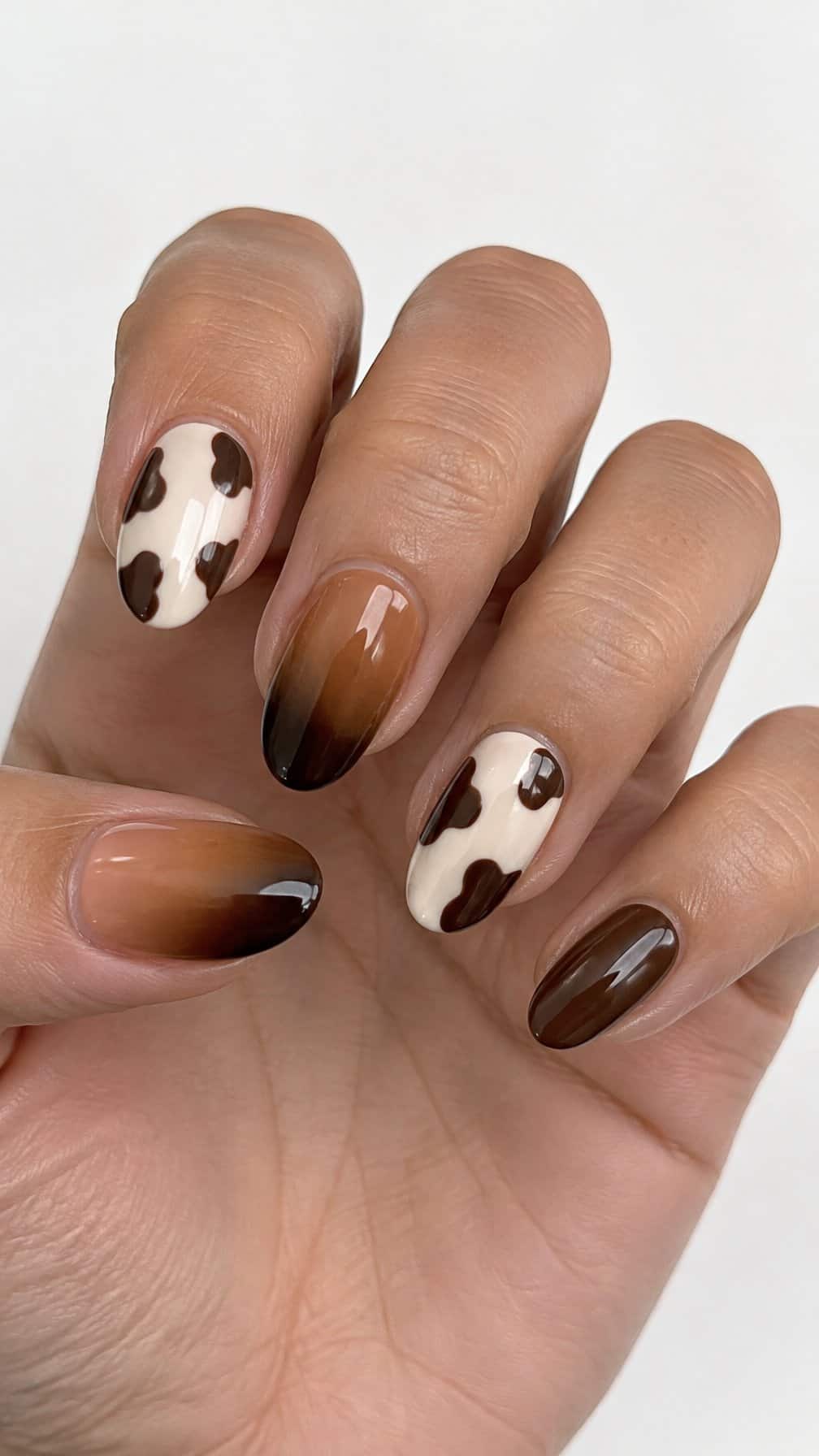 Glossy caramel, brown, and cream cow-print gel nails