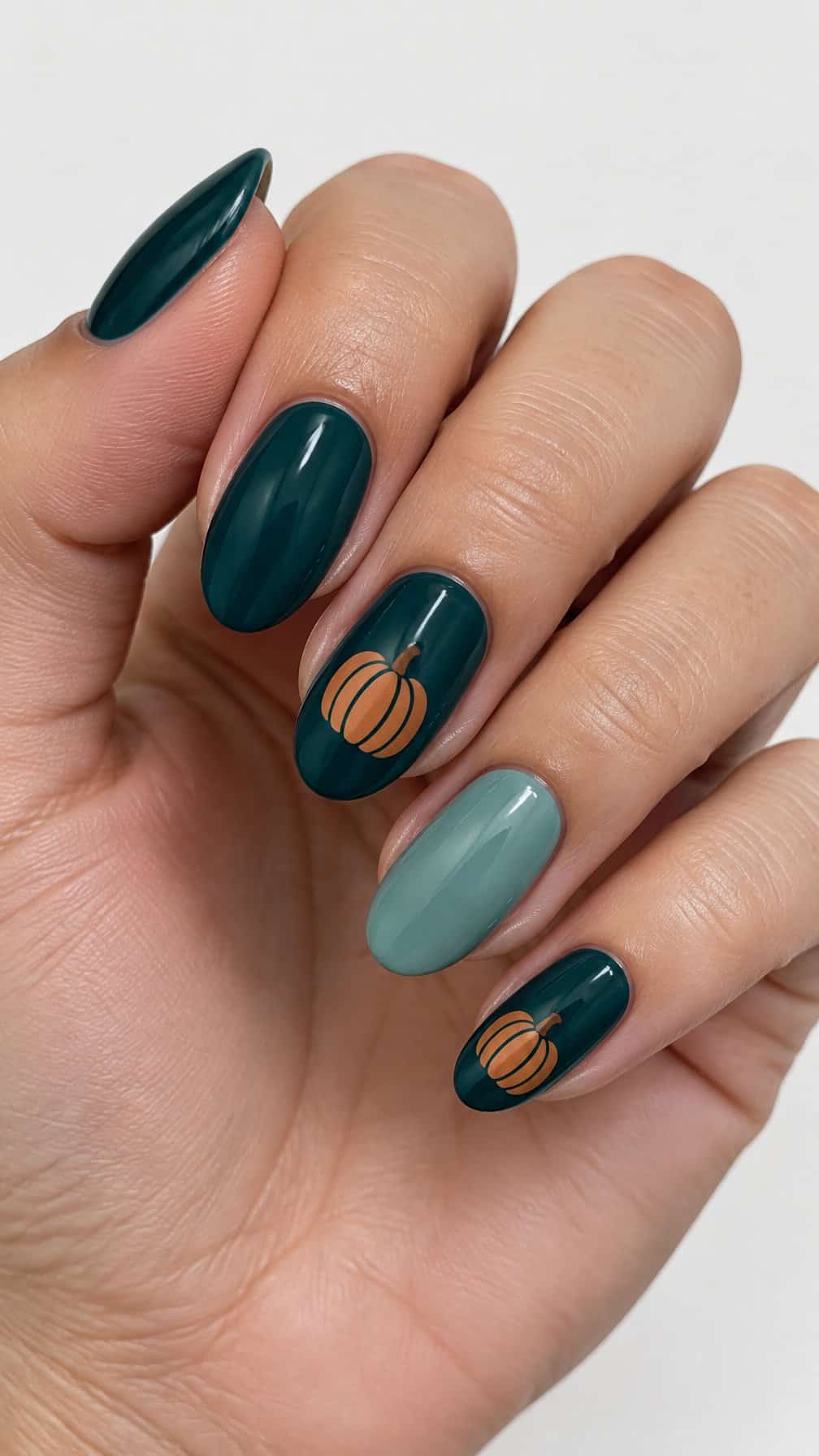 Glossy dark teal nails featuring small copper pumpkin designs