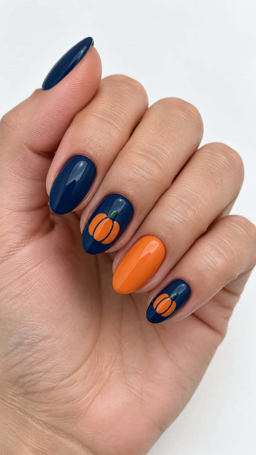 Glossy deep navy nails and small orange pumpkin designs on a few nails