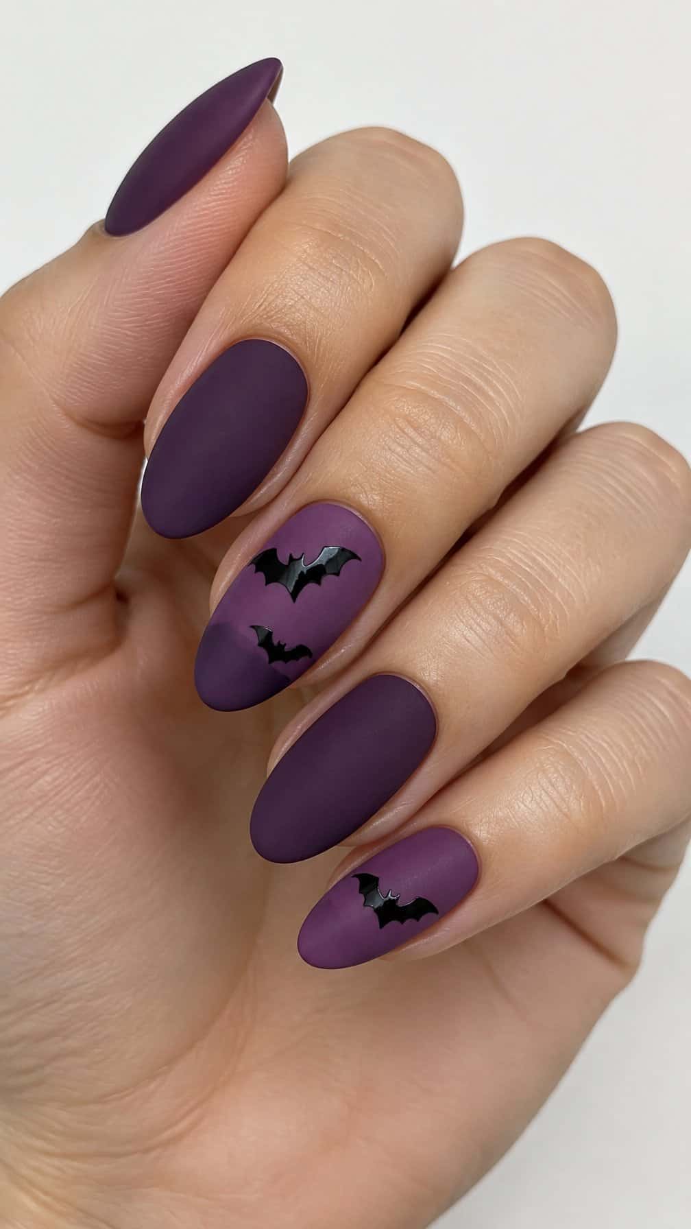 Matte purple nails and small glossy black bat designs