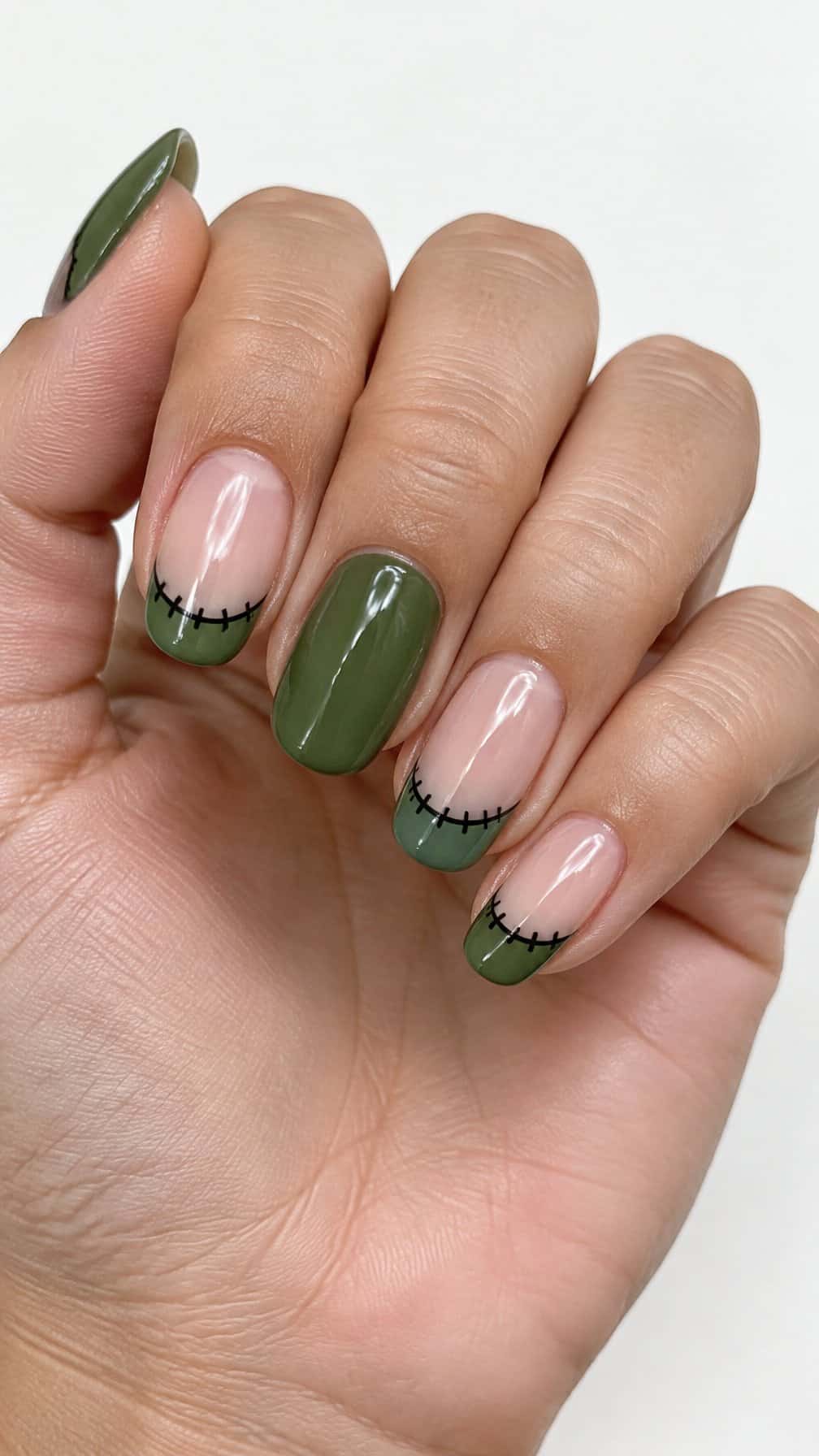 Glossy green French-tip nails decorated with black stitch details