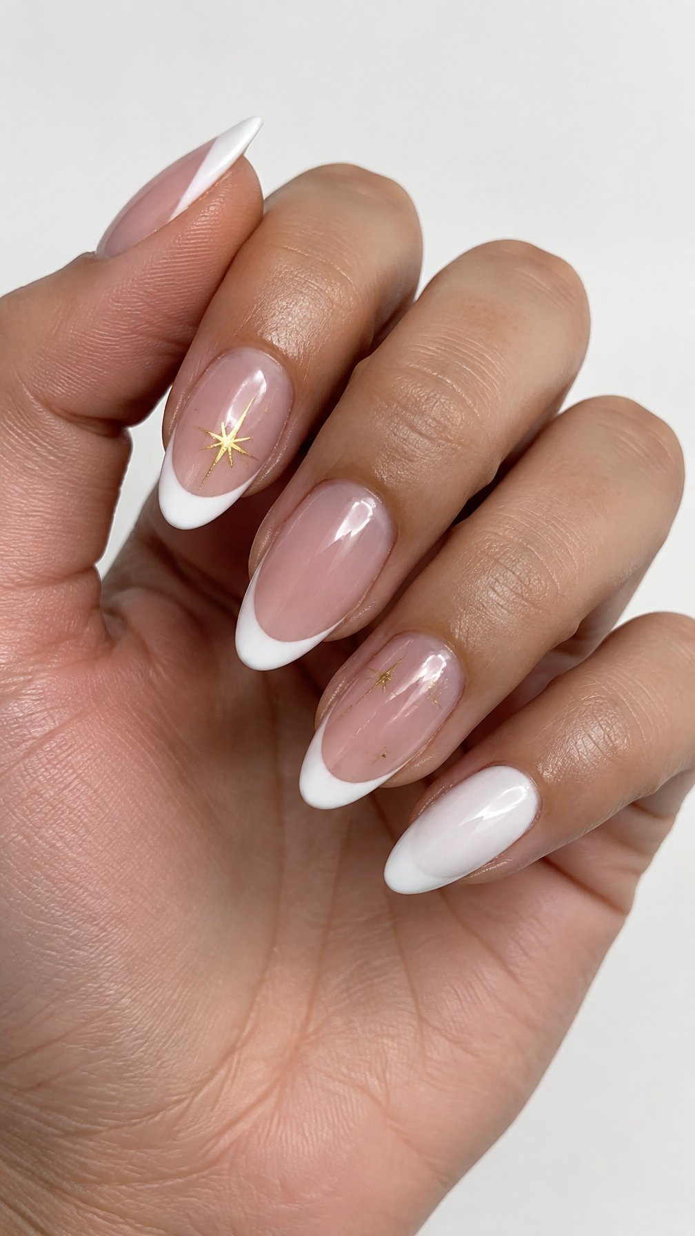 Glossy white French-tip nails and small gold starburst designs