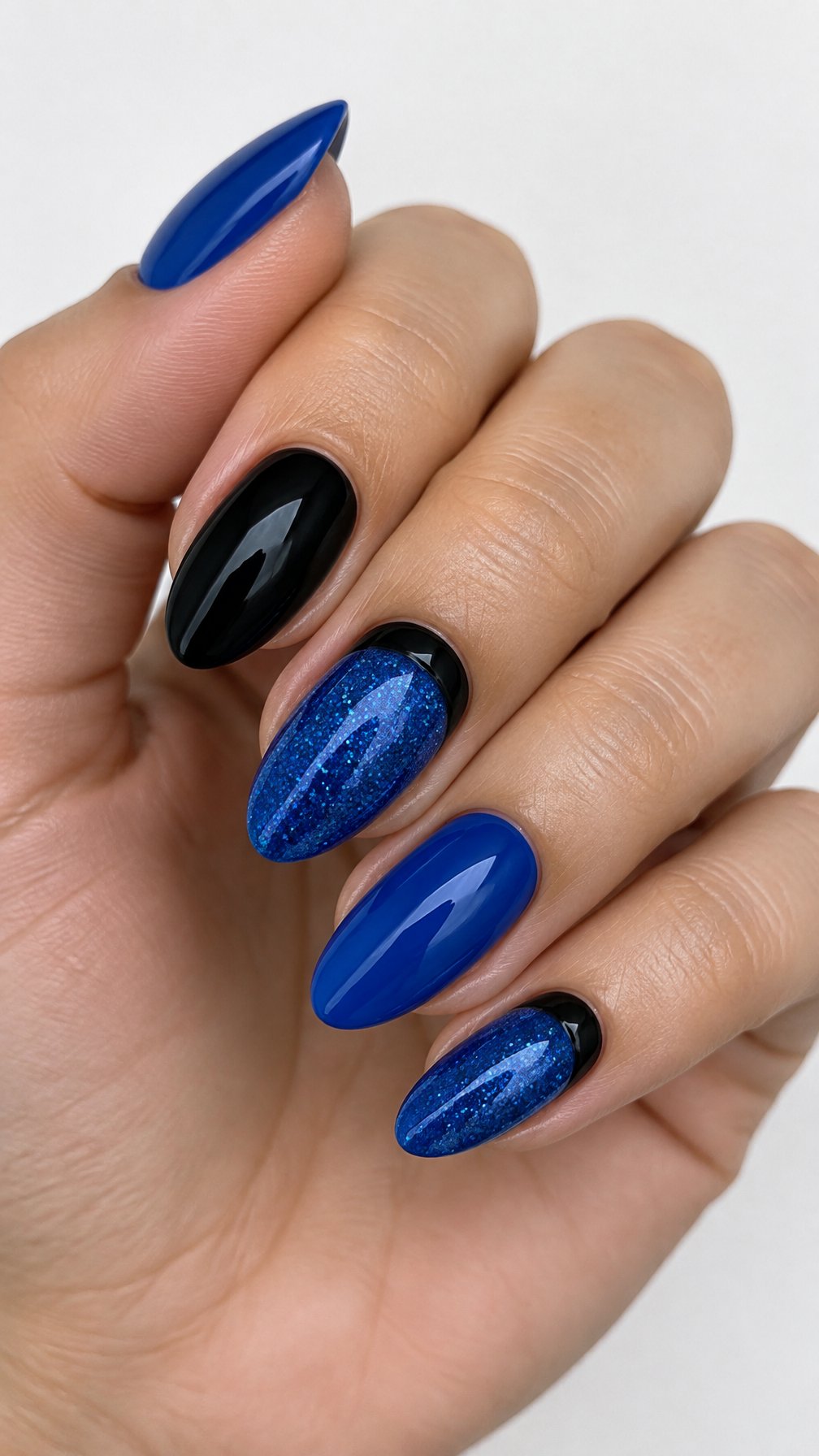 Glossy sapphire-blue and black manicure featuring glitter accents and dark cuticle details