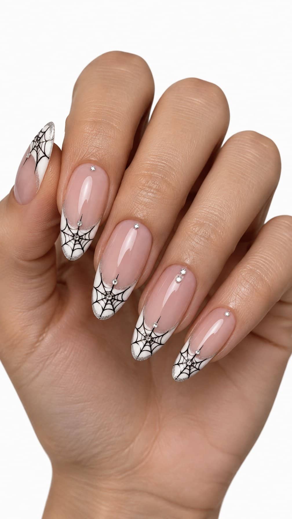 Nude, white-tipped nails decorated with glitter, spiderwebs, and small rhinestones