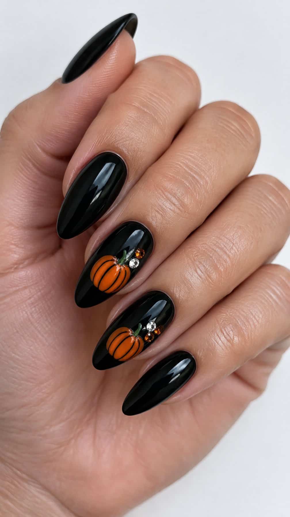 Glossy black and orange pumpkin-themed manicured nails