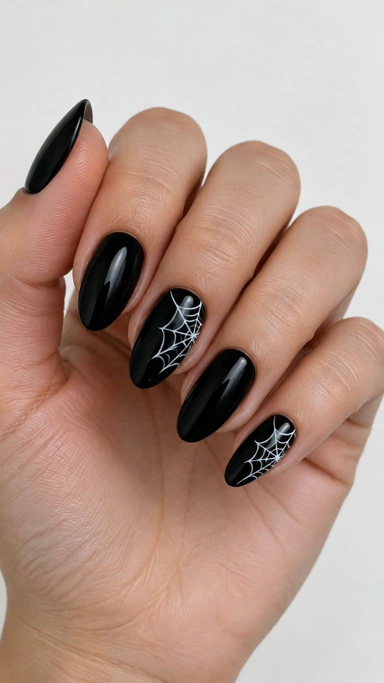 Glossy black gel nails, with white spider web designs on several accent nails