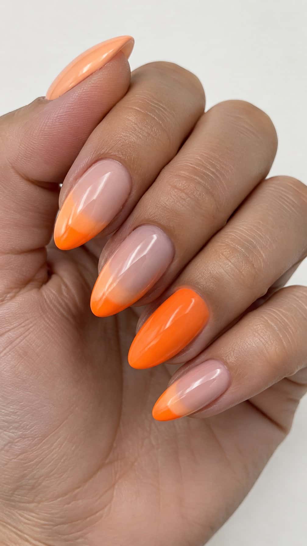 Glossy peach and neon orange French-tip nails
