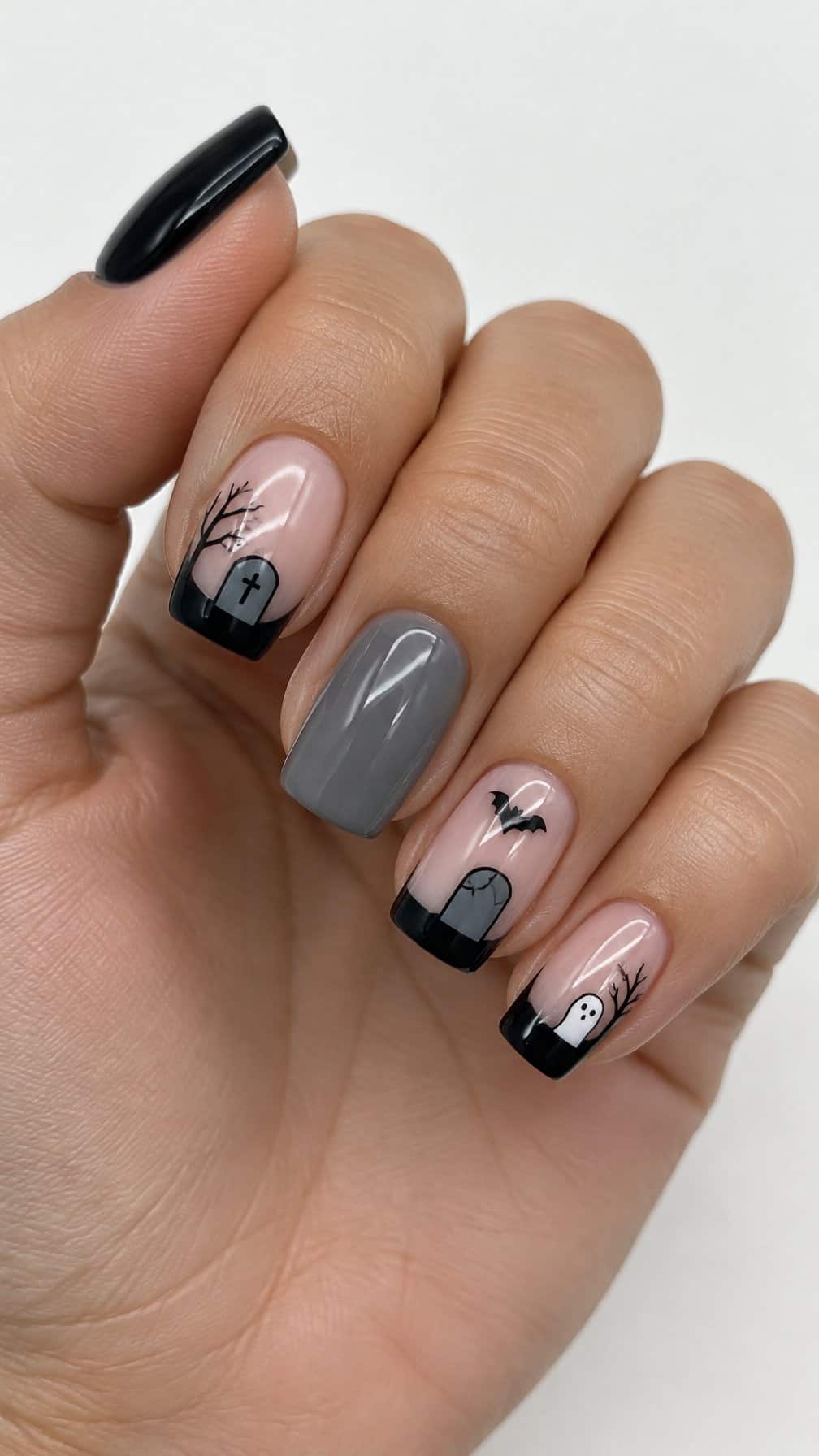 Glossy black and gray French-tip nails decorated with tiny tombstones