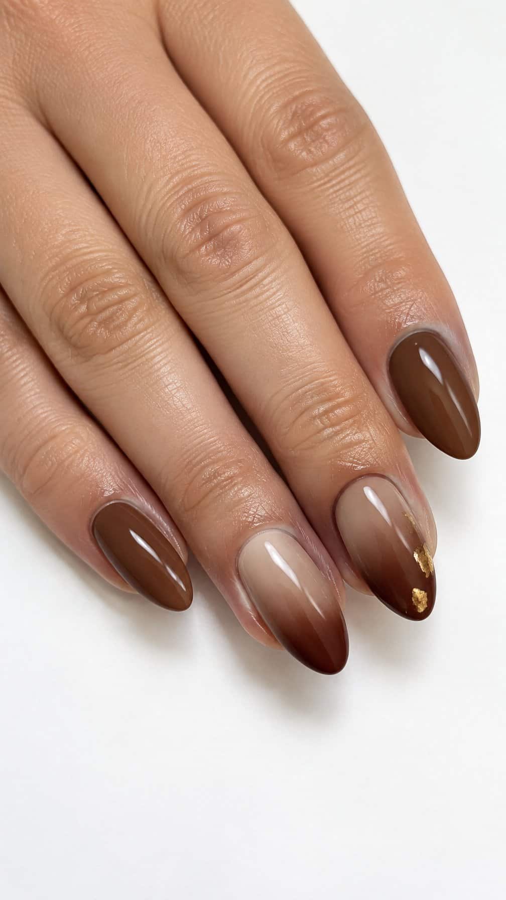 Glossy brown ombre nails with small gold foil accents