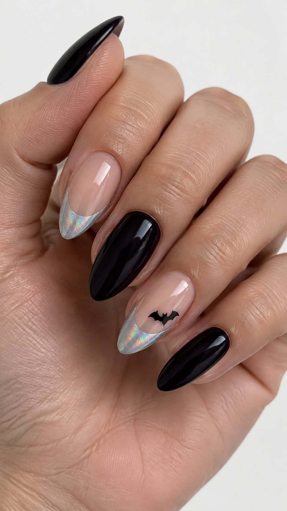Glossy holographic French-tip nails, dark solid nails, and small black bat designs