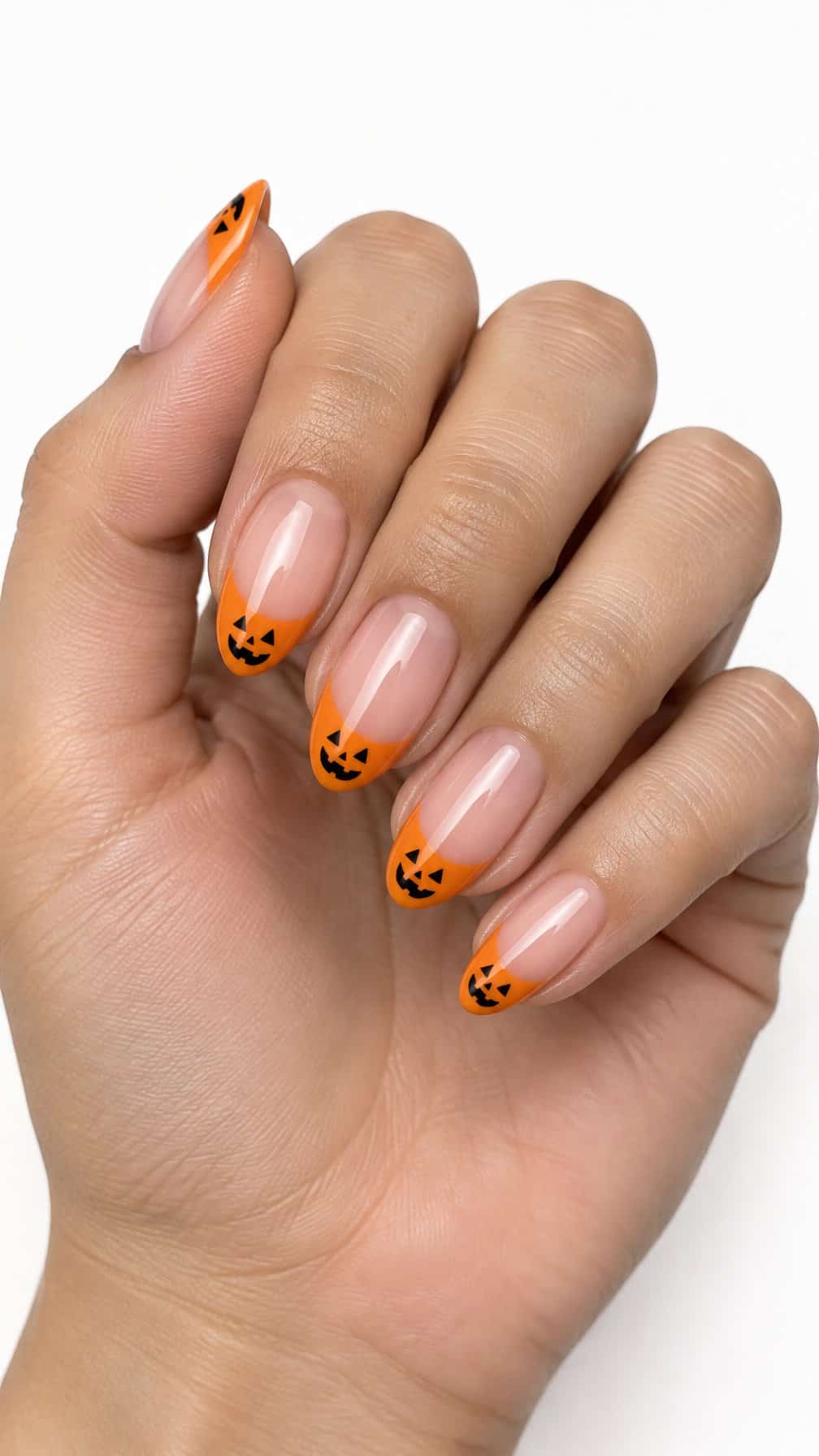 Glossy orange French tip nails decorated with tiny black jack-o'-lantern faces