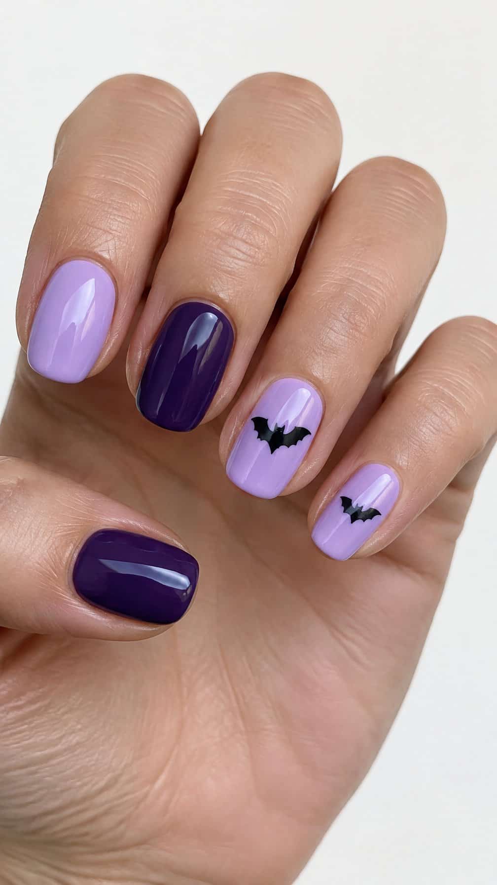 Lavender and purple gel nails featuring black bat silhouettes