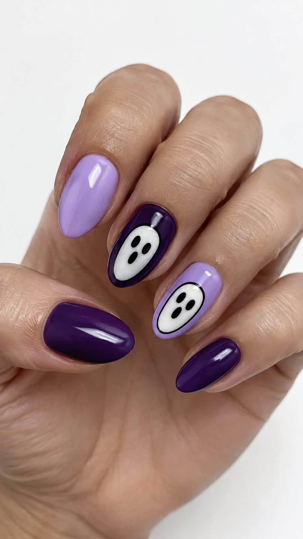 Glossy lavender and purple nails featuring simple white ghost faces on two accent nails