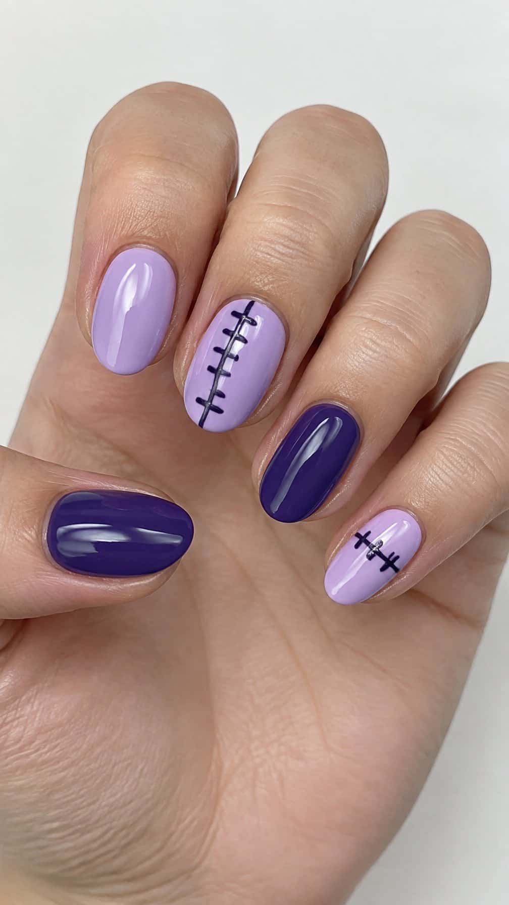 Glossy lilac and purple nails decorated with dark stitched lines
