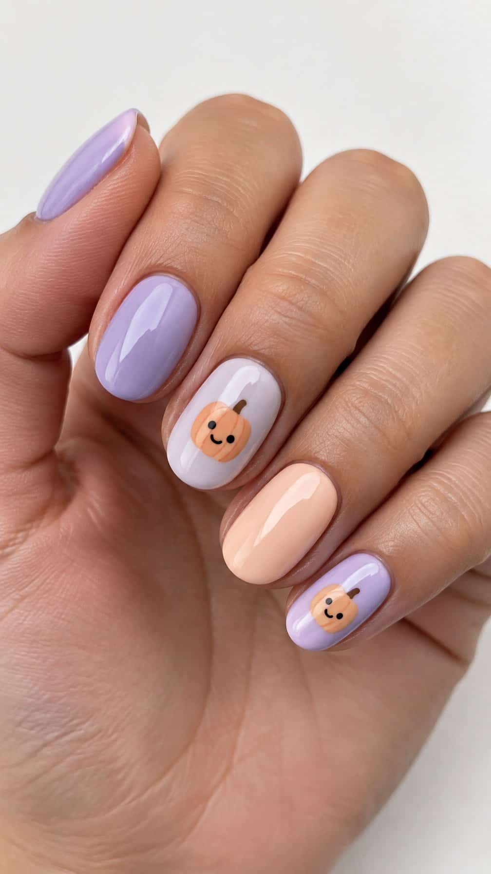 Glossy lilac nails, some decorated with cute pastel pumpkin faces