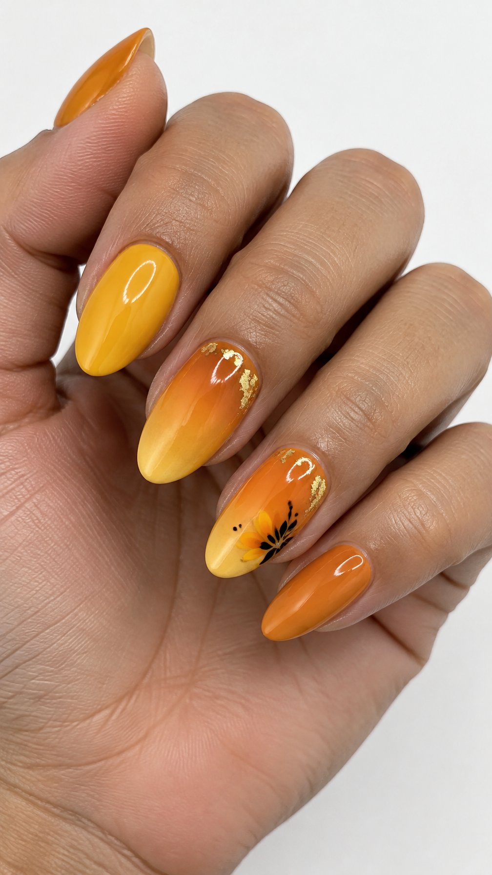 Glossy marigold ombré nails, gold foil accents, and simple decorative details