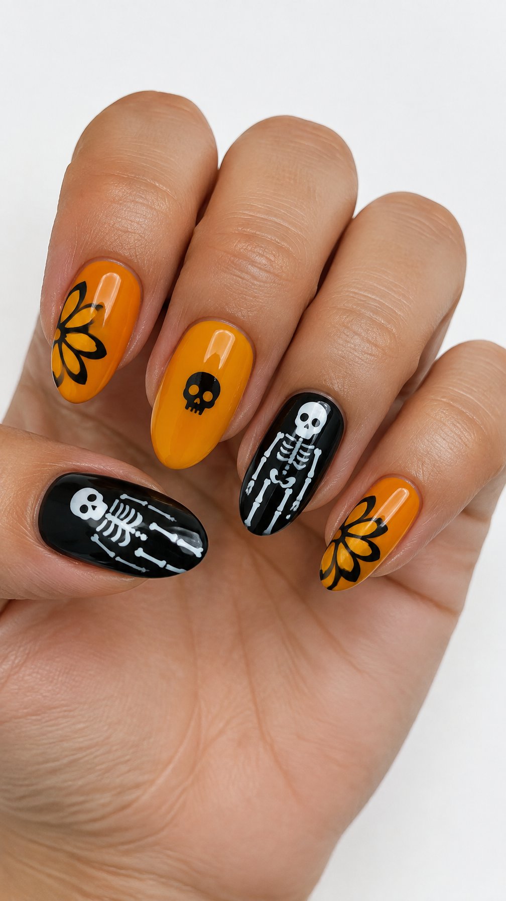A glossy black, white, and orange skeleton and marigold manicure
