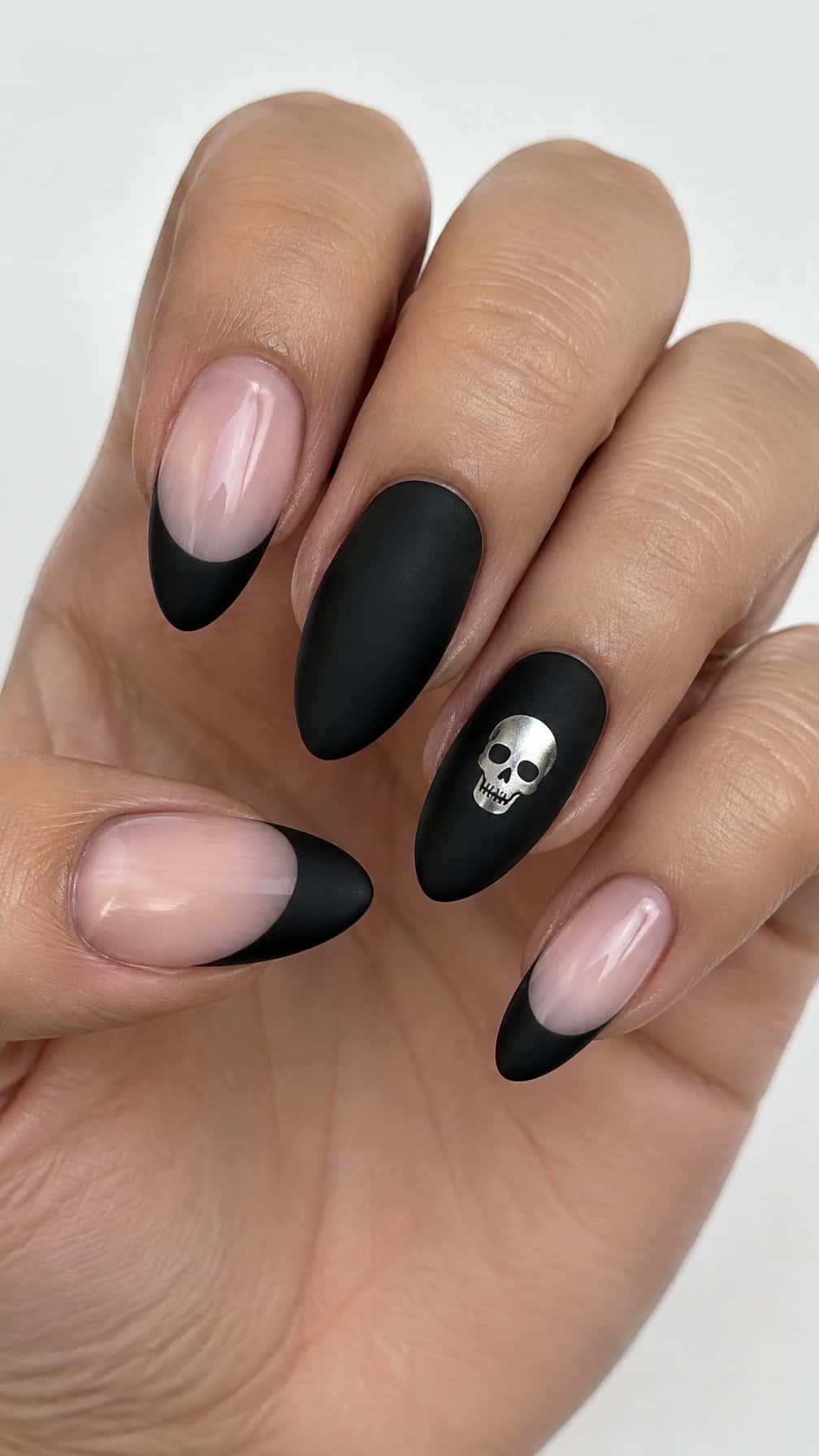 A black French tip manicure and a small silver skull design on one nail