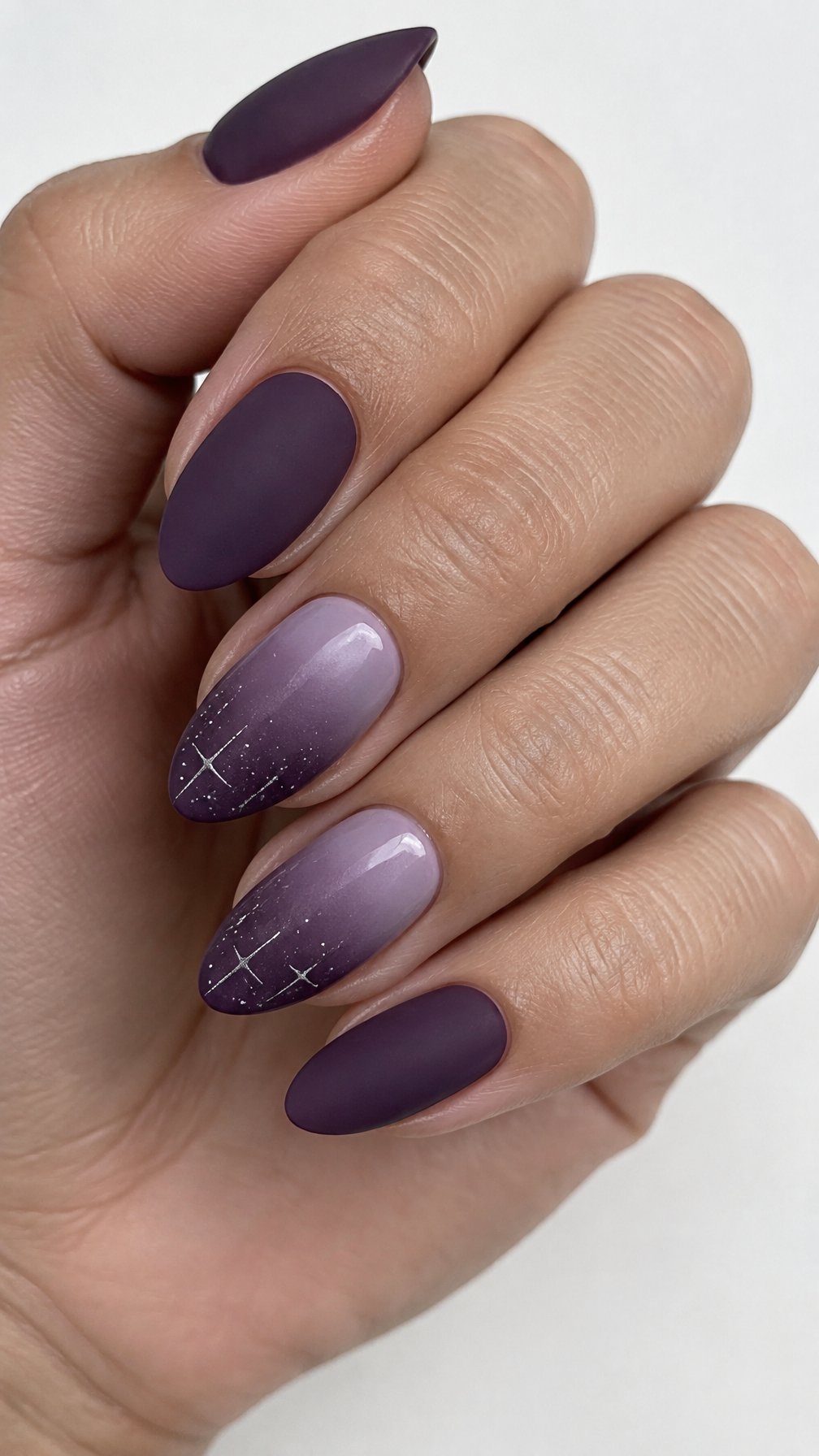 A plum purple manicure with lavender ombré accents and small glitter stars near the tips