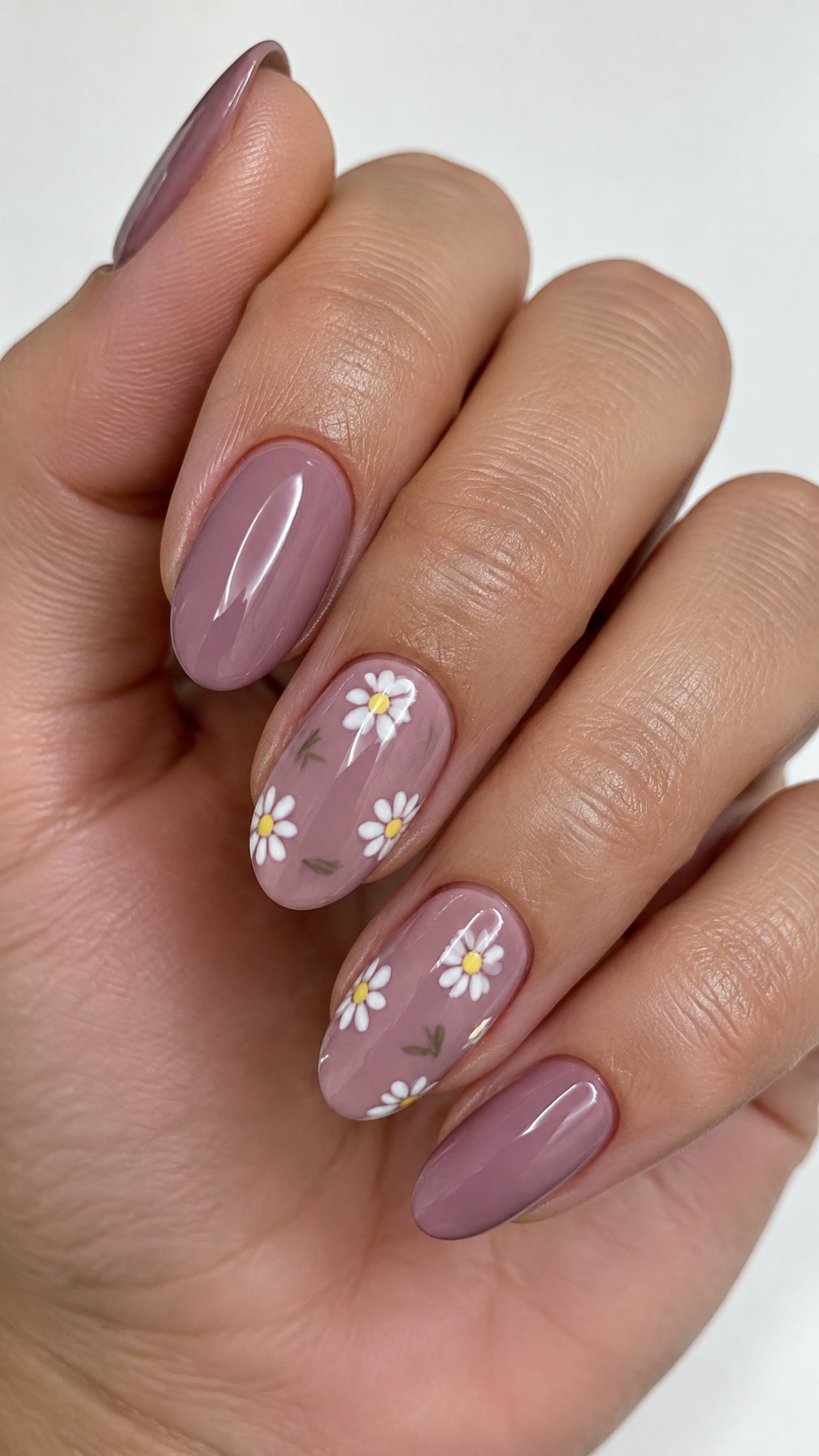 Mauve polished nails featuring small white daisy designs on a few nails