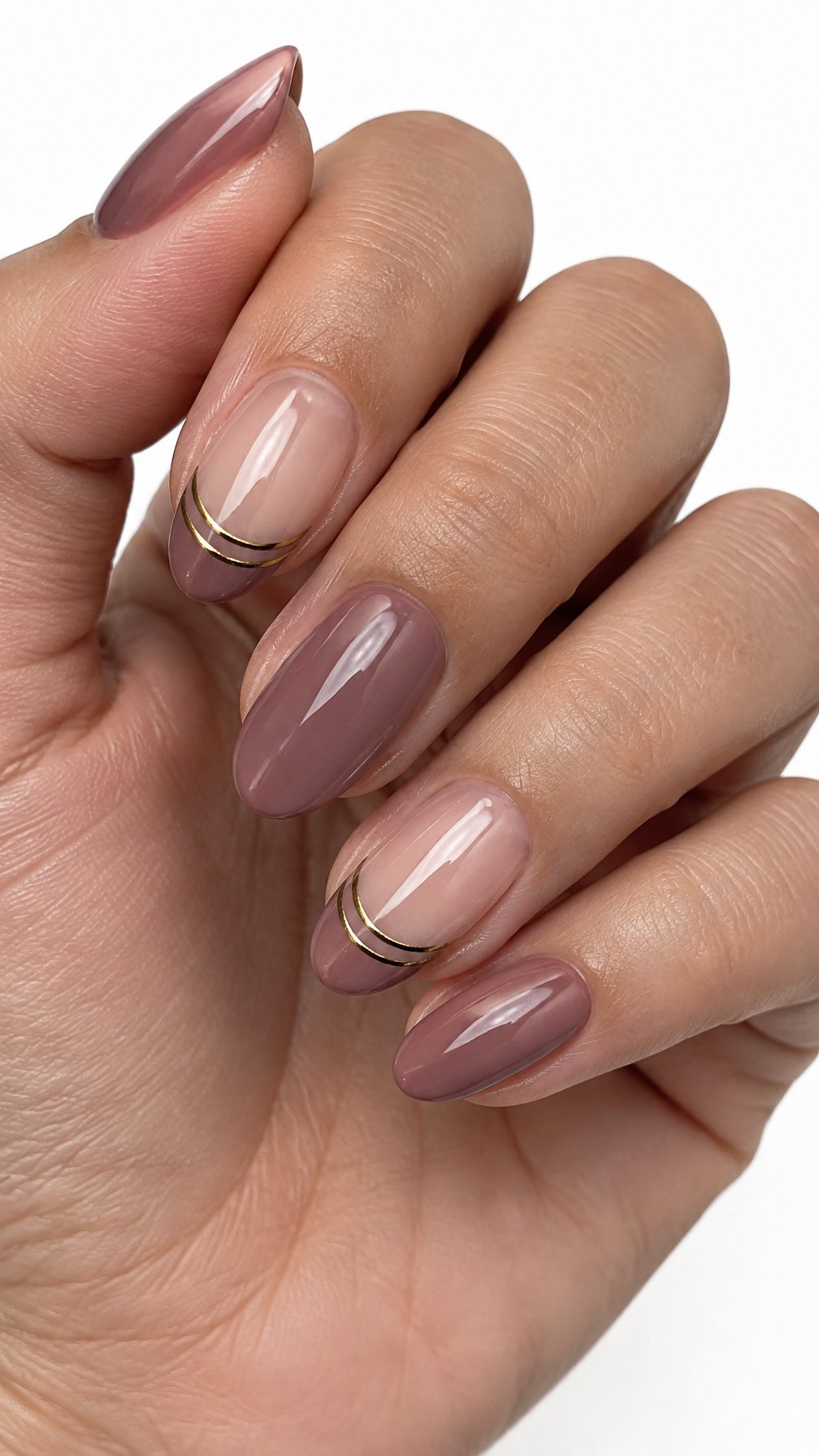 Glossy warm mauve French-tip nails accented by thin gold double lines