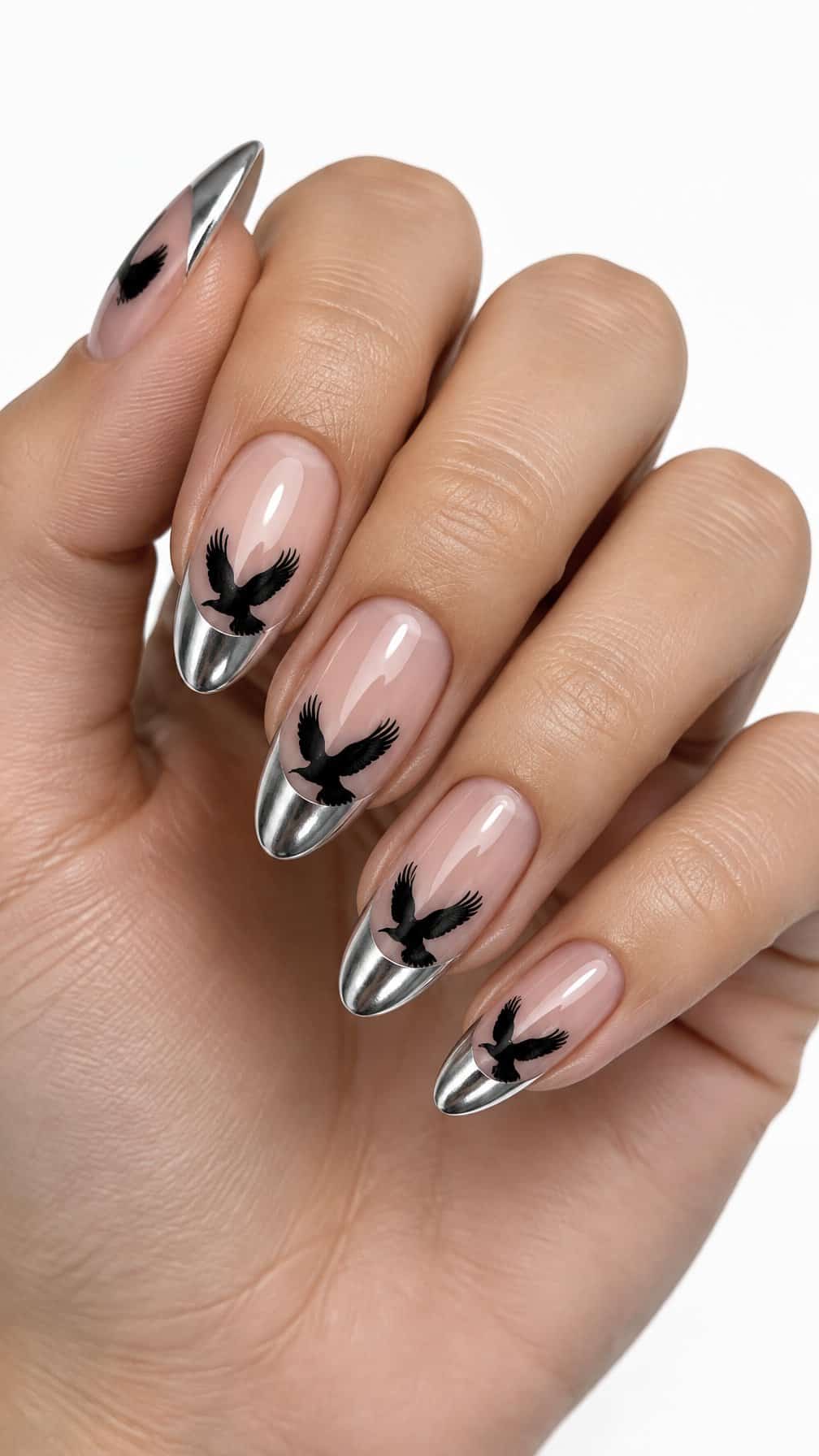 Glossy metallic silver French-tip nails decorated with black raven silhouettes
