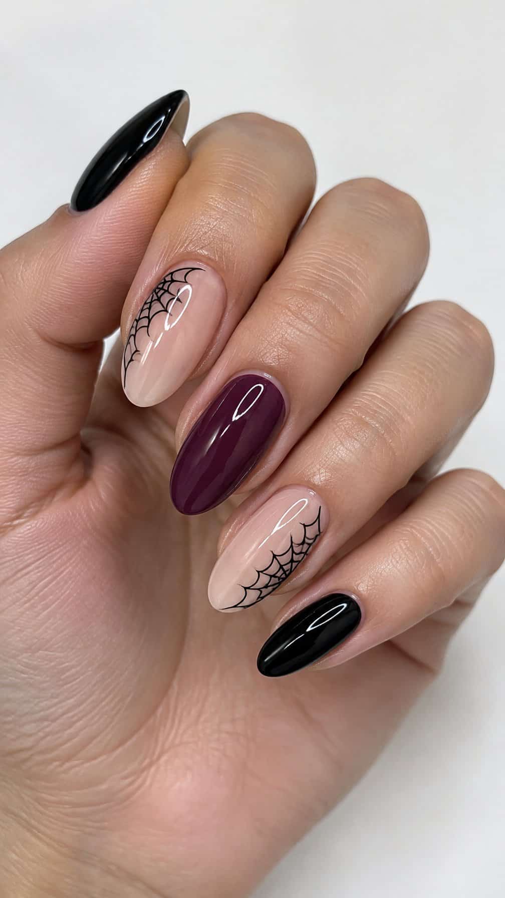 Glossy black, burgundy, and nude nails featuring simple spider web designs
