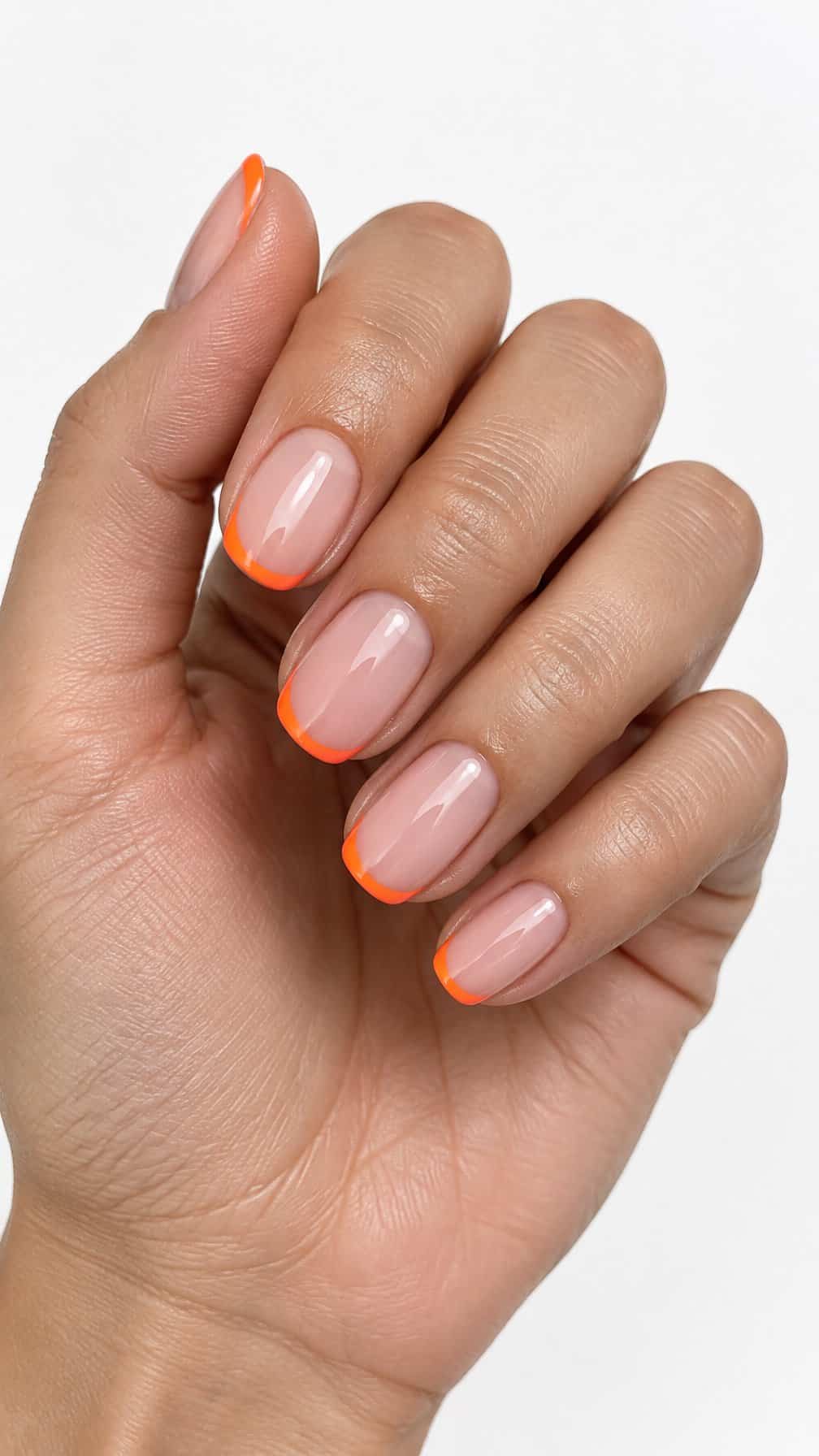 Glossy nude nails featuring thin neon orange French tips