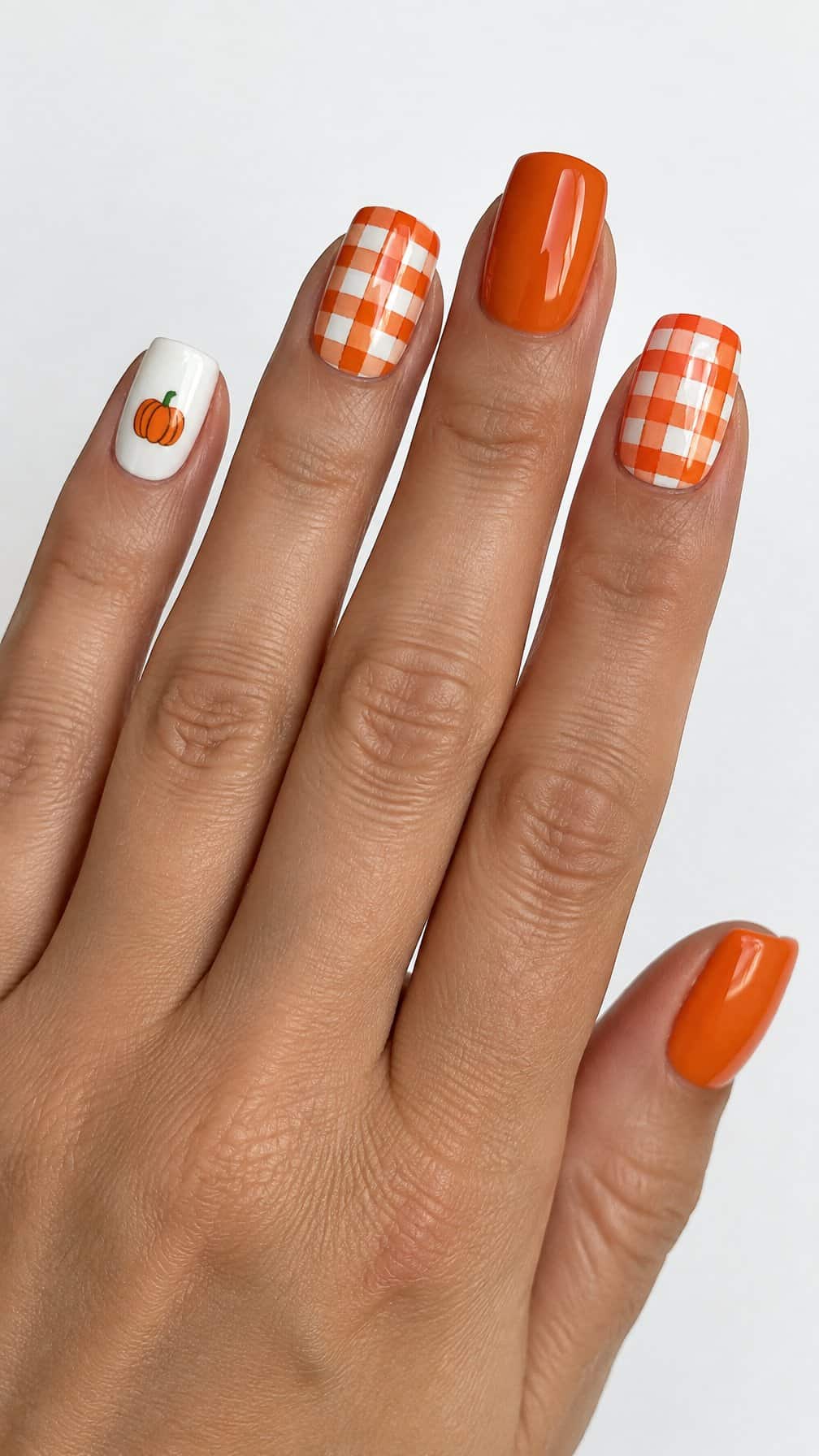 Glossy orange and white gingham nails and small pumpkin designs