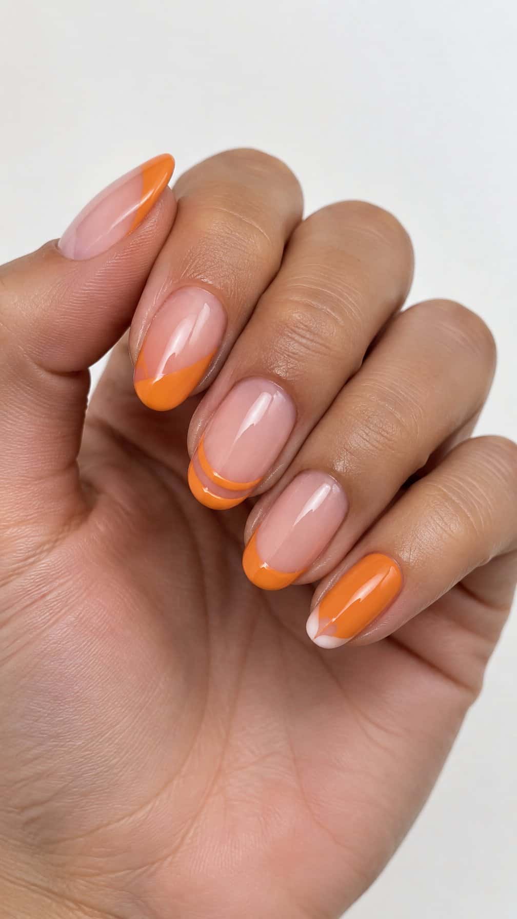 Five glossy orange French-tip manicured nails