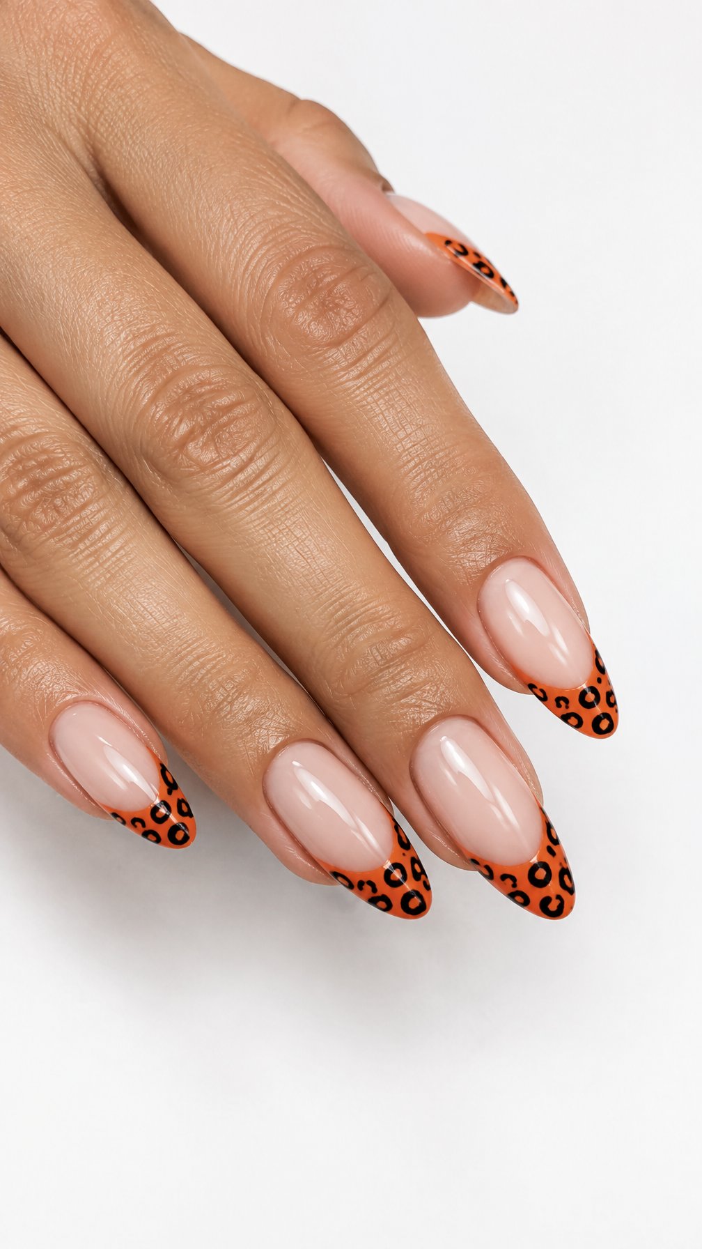 Glossy orange French-tip nails decorated with black leopard spots