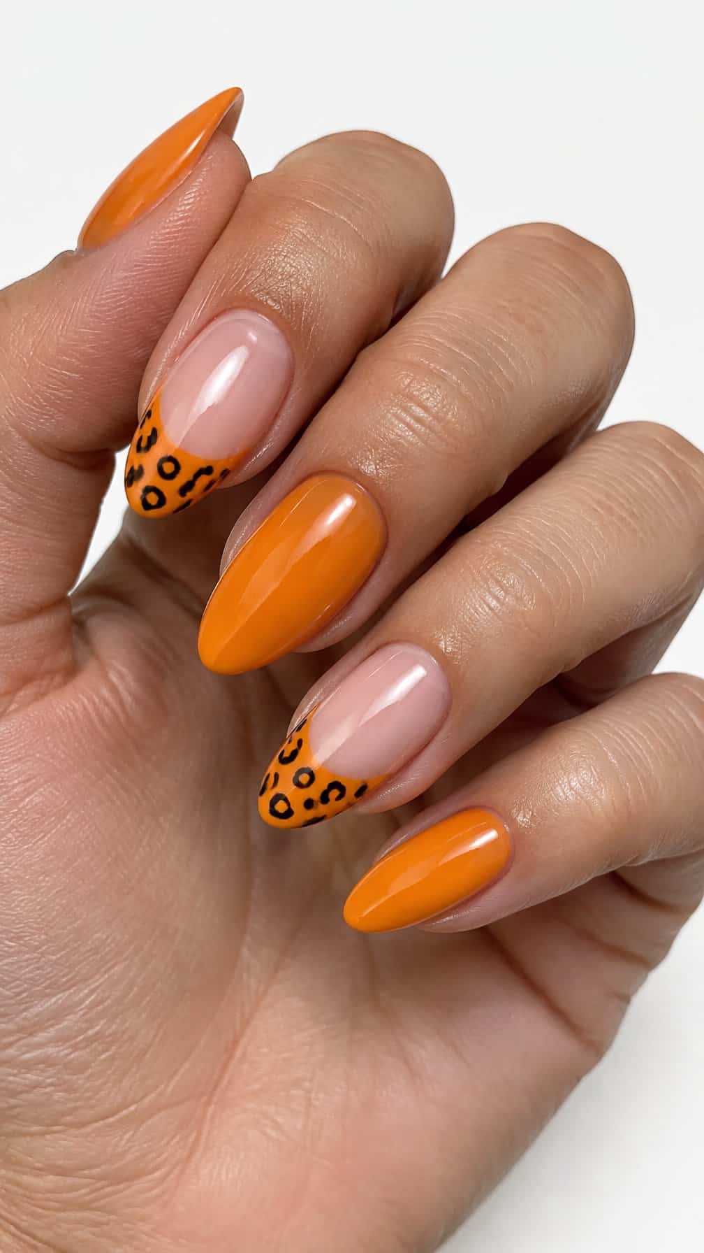 Orange French-tip nails decorated with black leopard spots