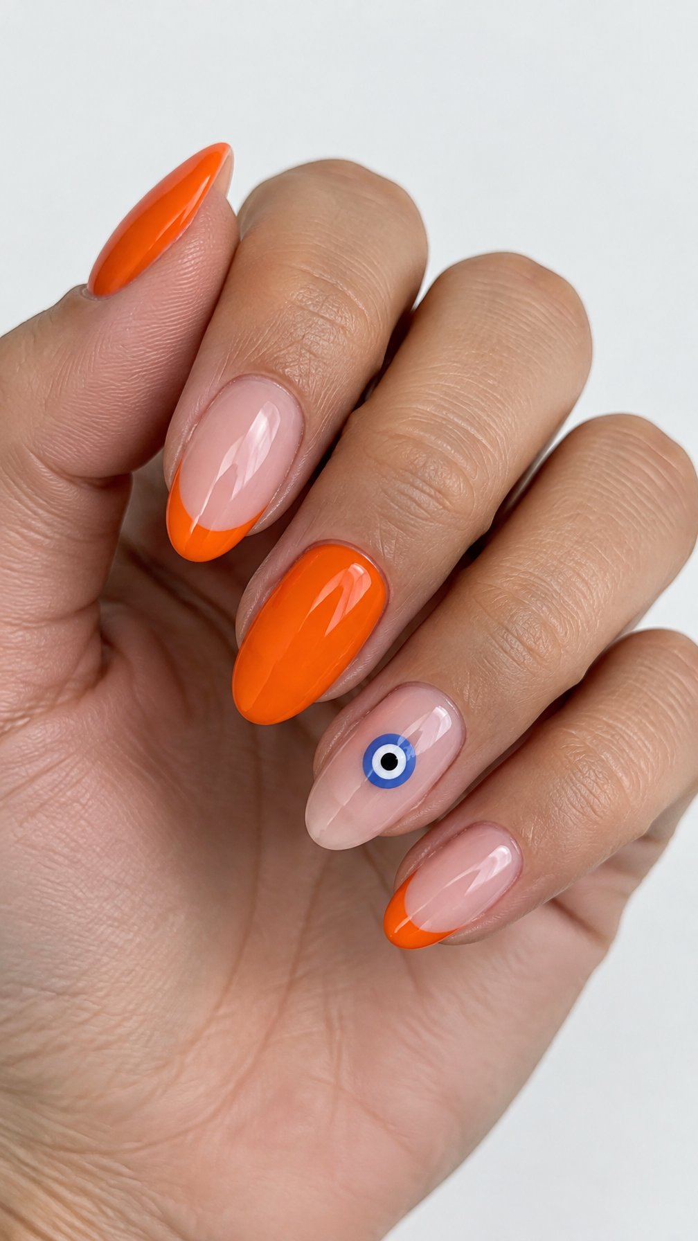 Glossy orange French tip nails with blue eye designs on a few accent nails