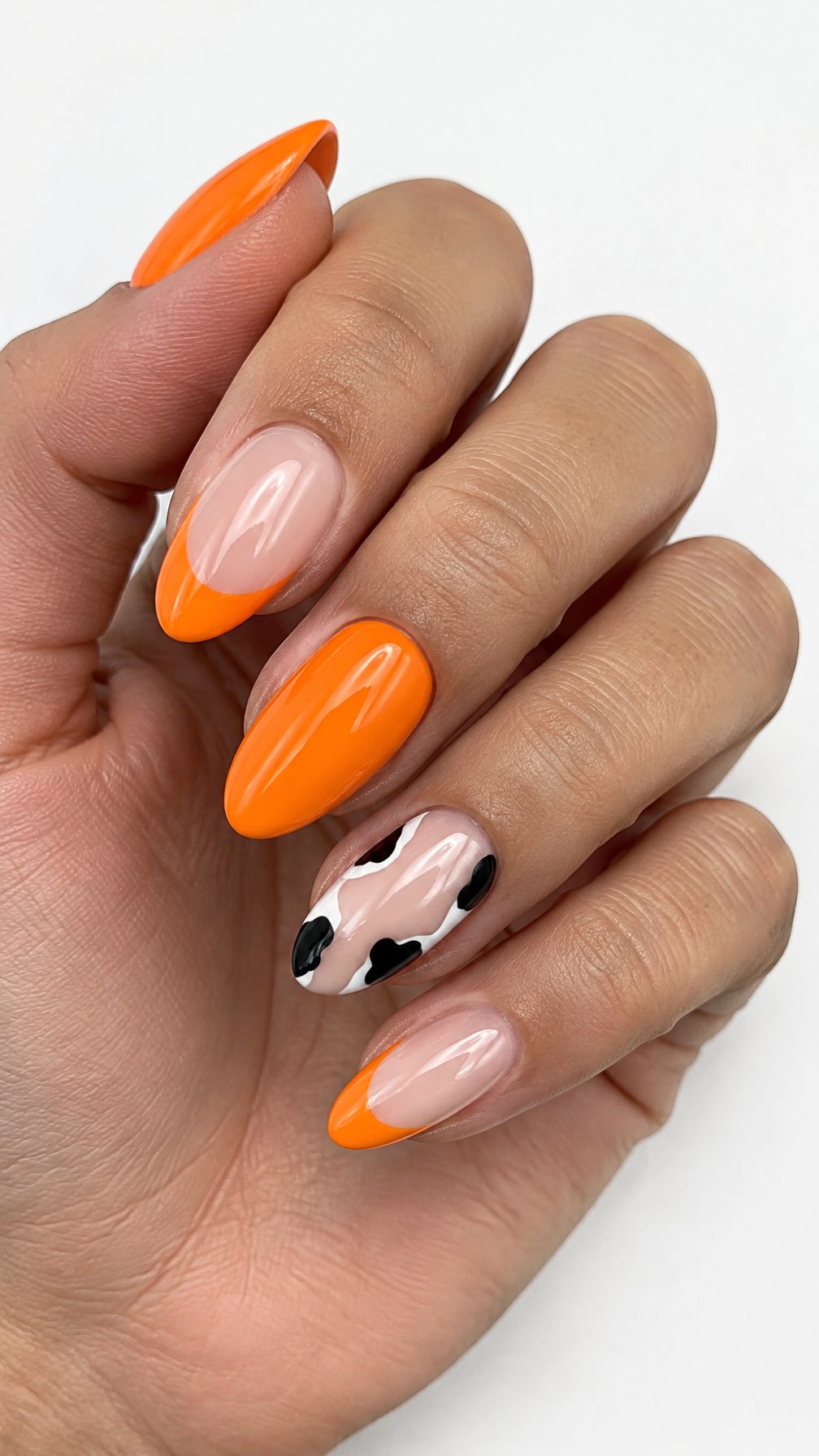 Glossy orange French tip nails and black-and-white cow-print accent nails