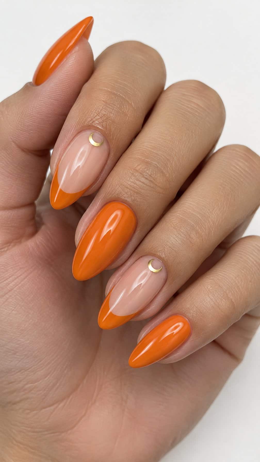 Orange French tip nails, glossy solid orange nails, and small gold crescent moons