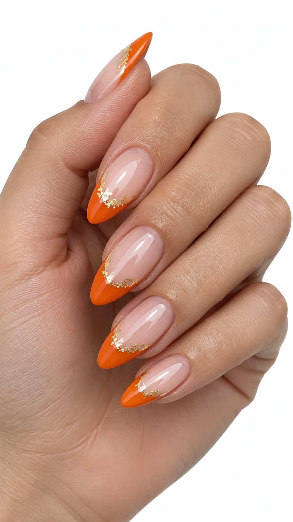 Glossy nude nails, bright orange French tips, and small gold foil accents