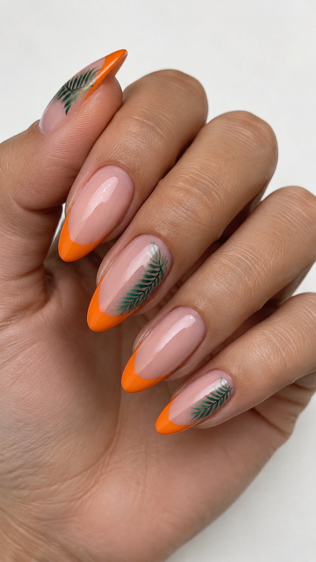 Glossy orange French-tip nails and delicate green palm leaf designs
