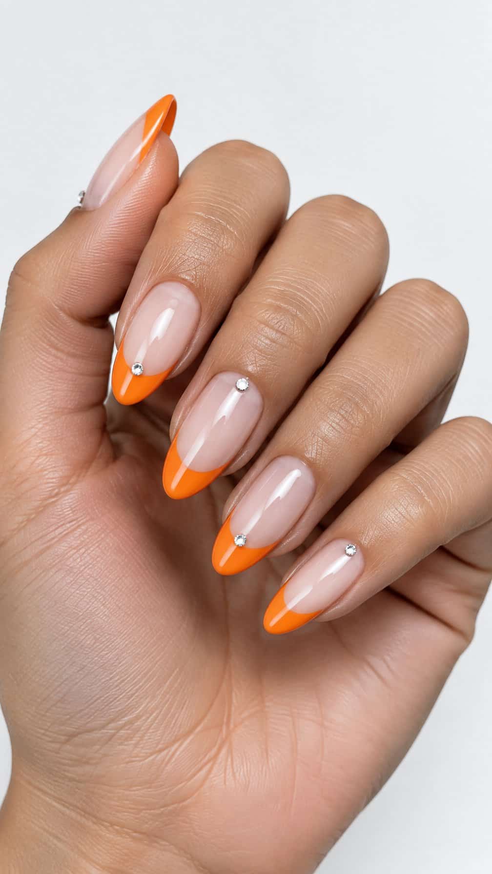 Glossy orange French tip nails and tiny rhinestones