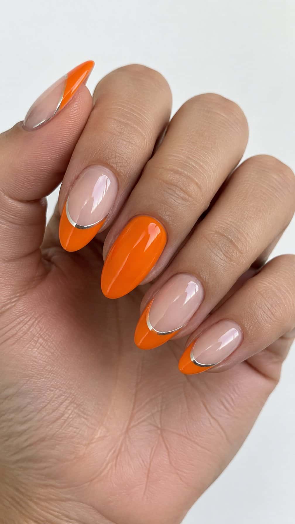 Glossy orange French tip nails accented by thin silver lines