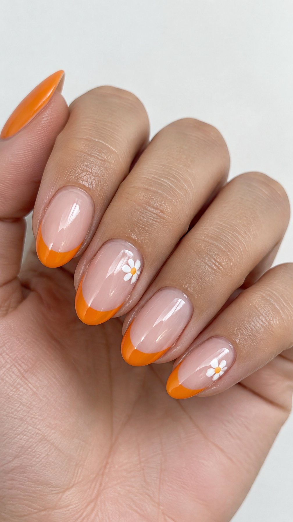Glossy orange French tip nails and tiny white daisies