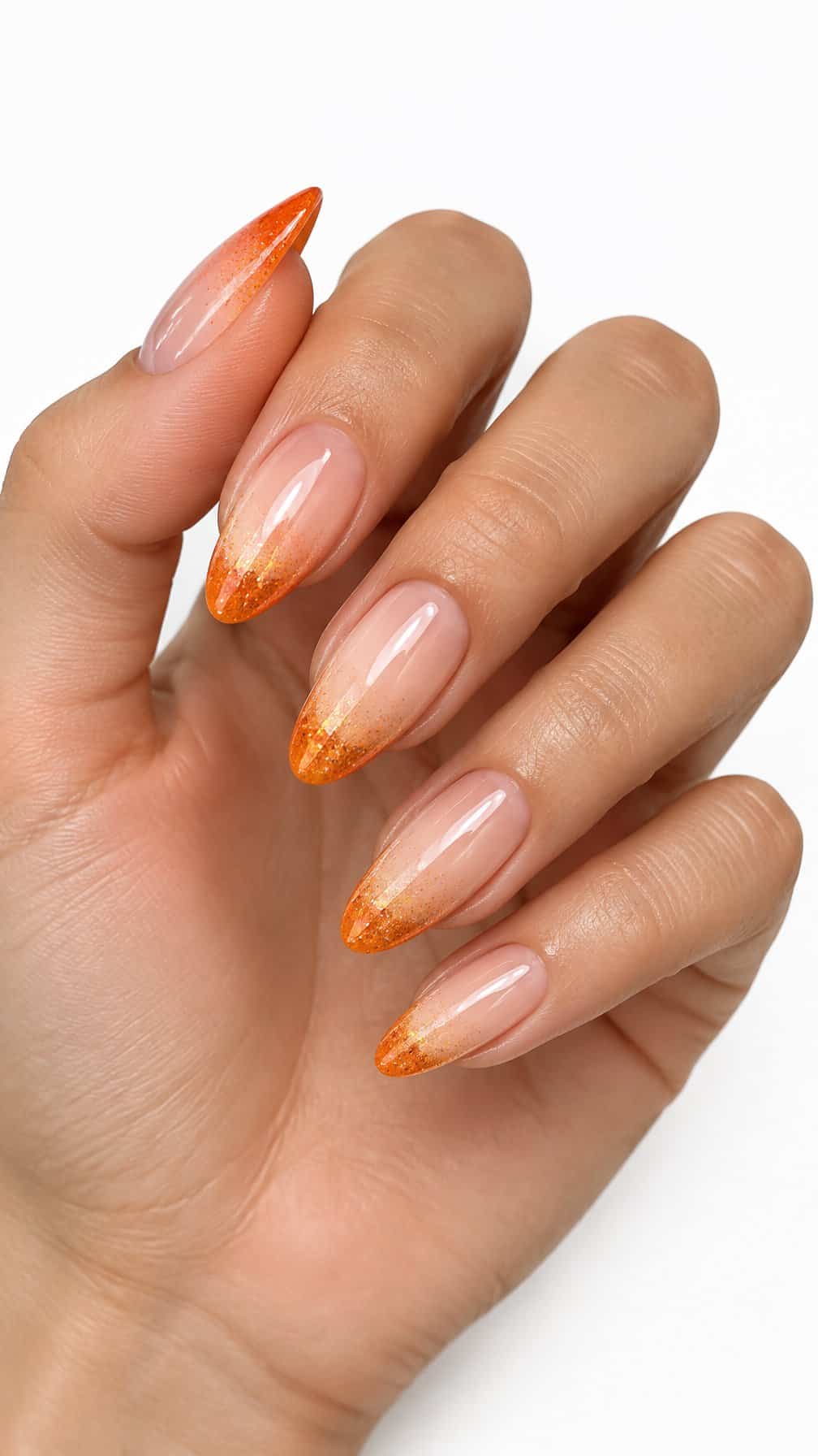 Almond-shaped nails featuring sparkling orange ombré French tips