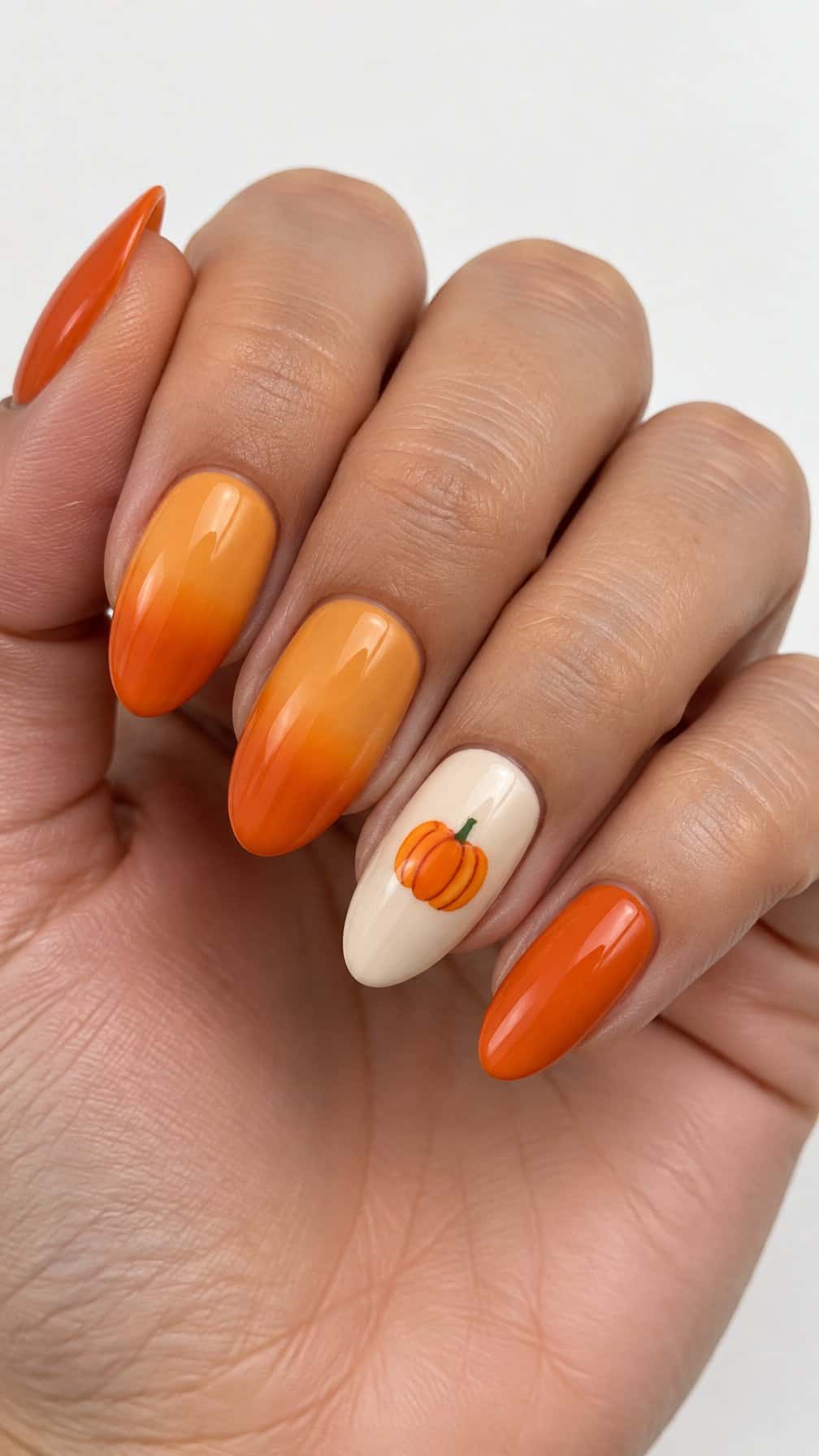 Glossy orange ombré nails and one small pumpkin design on an accent nail