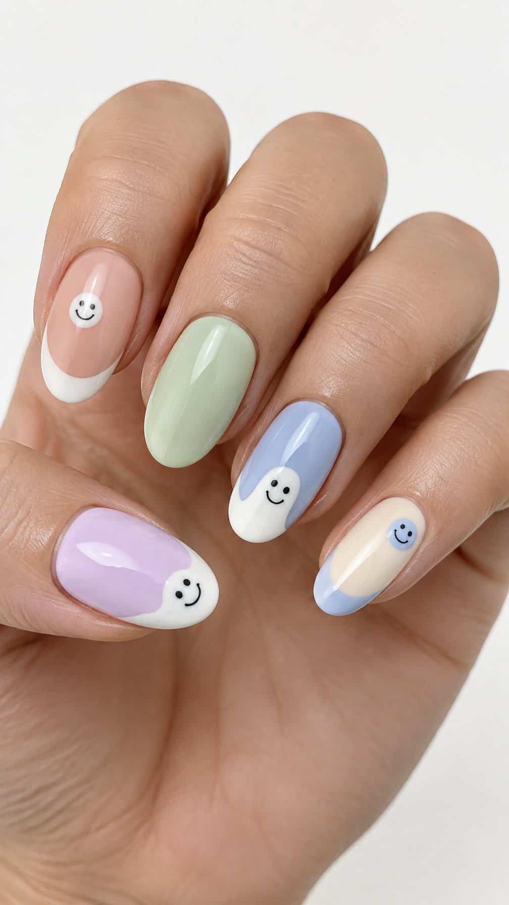 Pastel French-tip nails decorated with small ghost and smiley-face designs