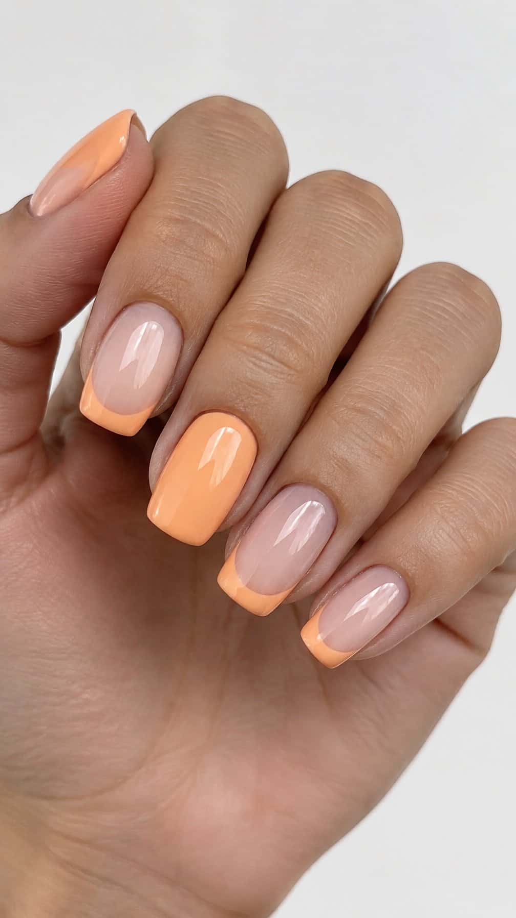 Peach French tip nails on a milky nude base