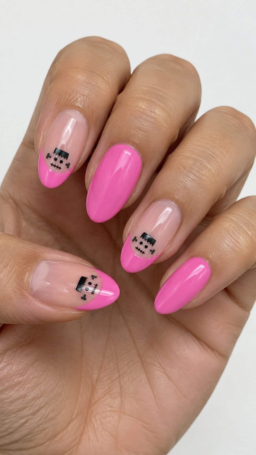 Glossy pink French-tip nails decorated with tiny Frankenstein faces