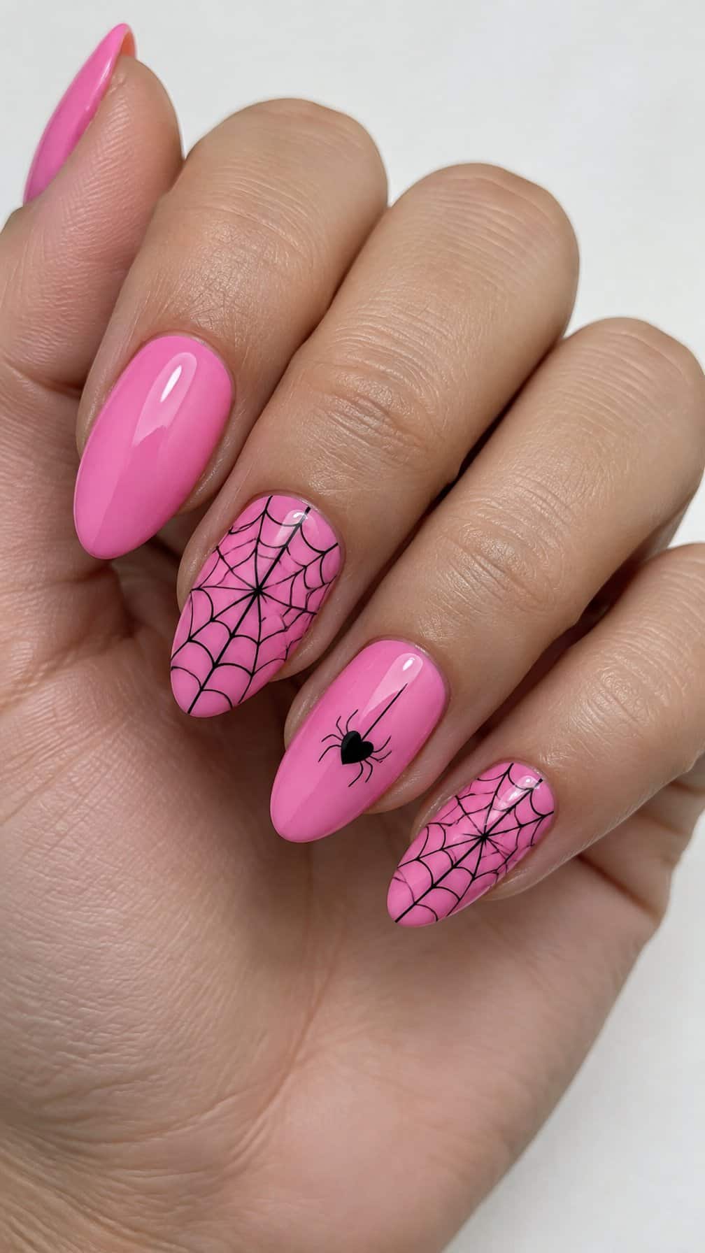 Glossy pink nails decorated with black spider webs and small heart-shaped spiders