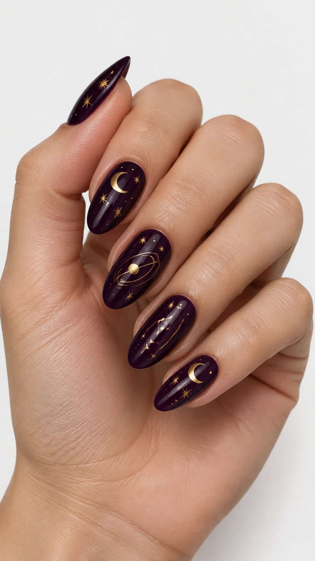 Glossy plum-purple almond-shaped nails decorated with small gold moons and stars