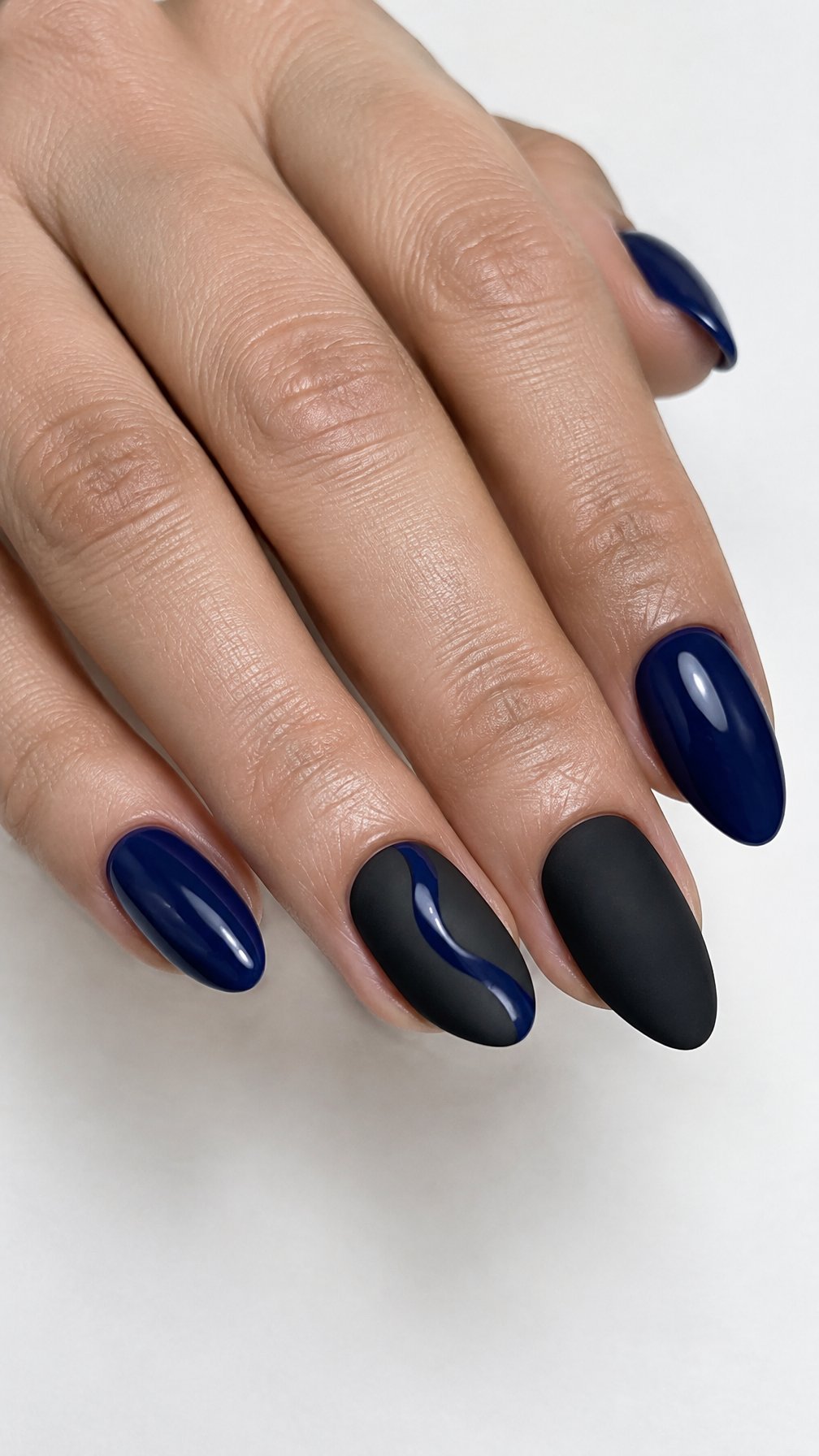Matte black nails with glossy navy-blue swirls and solid navy nails