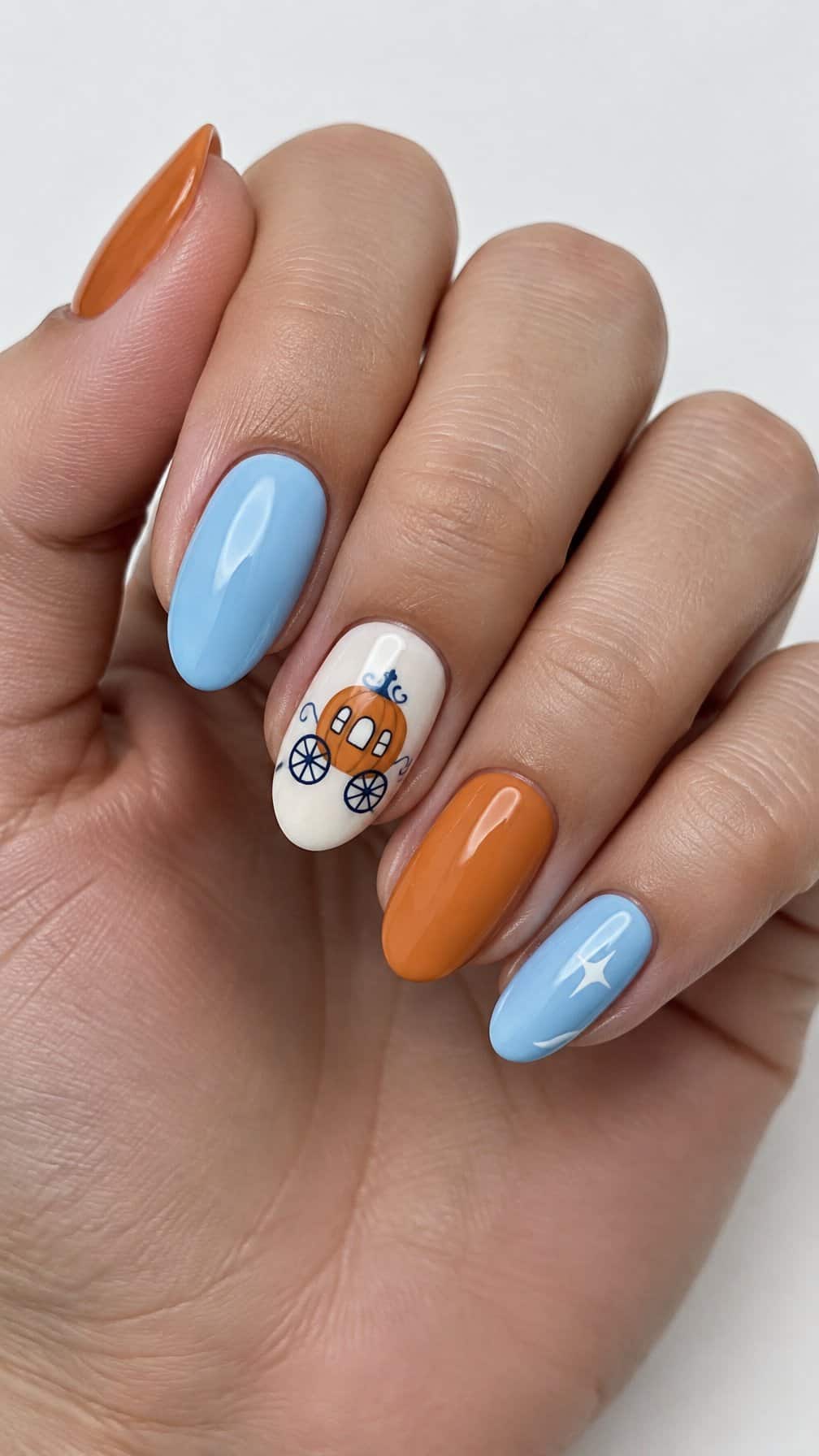 Glossy pumpkin orange and pale blue nails, including a small pumpkin carriage design