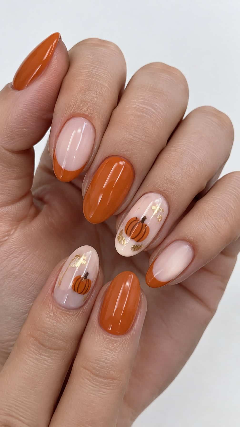 Pumpkin-themed orange and gold manicured nails